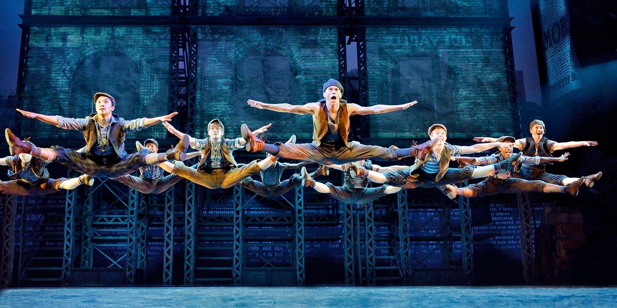 Performers mid-air in a synchronized jump during a theatrical dance show.