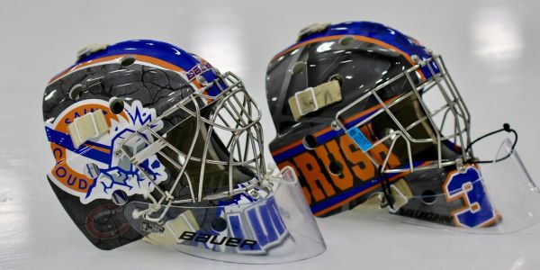 Two ice hockey goalie masks with blue and orange designs.