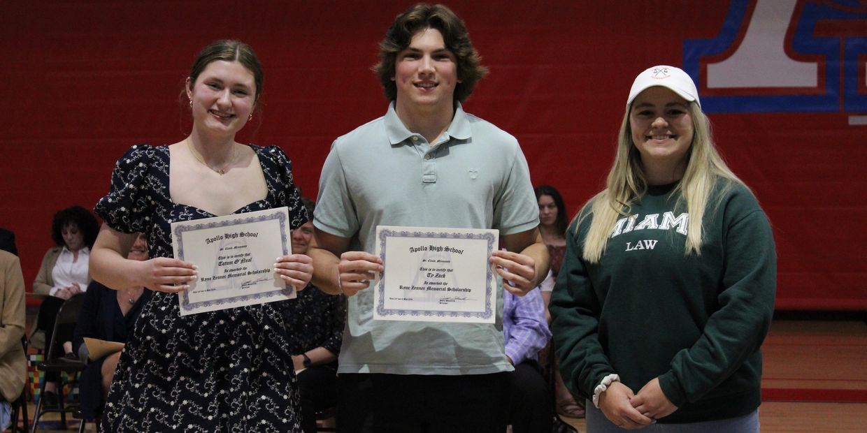 Three students posing, two holding certificates.