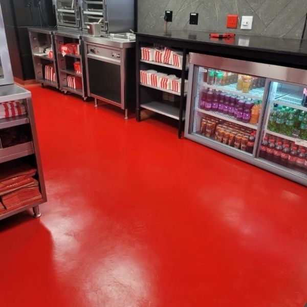 Another successful KFC installation. Clean commercial kitchen area with stainless steel appliances and red flooring.