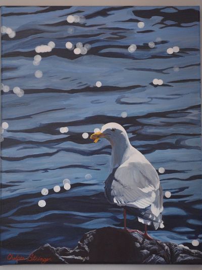 A seagull perched by rippling blue water with light reflections.