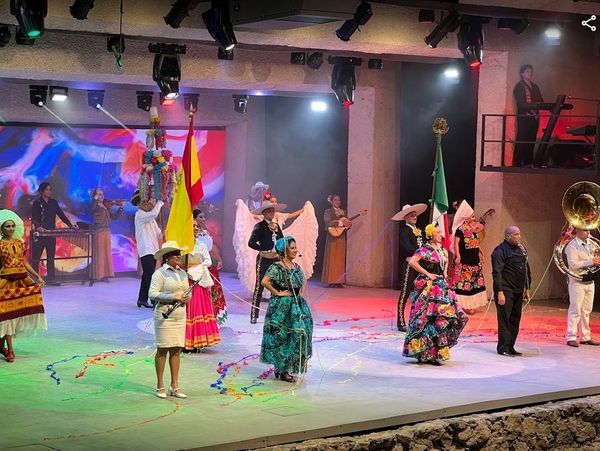 Performers in traditional Mexican attire on a colorful stage during a cultural show.