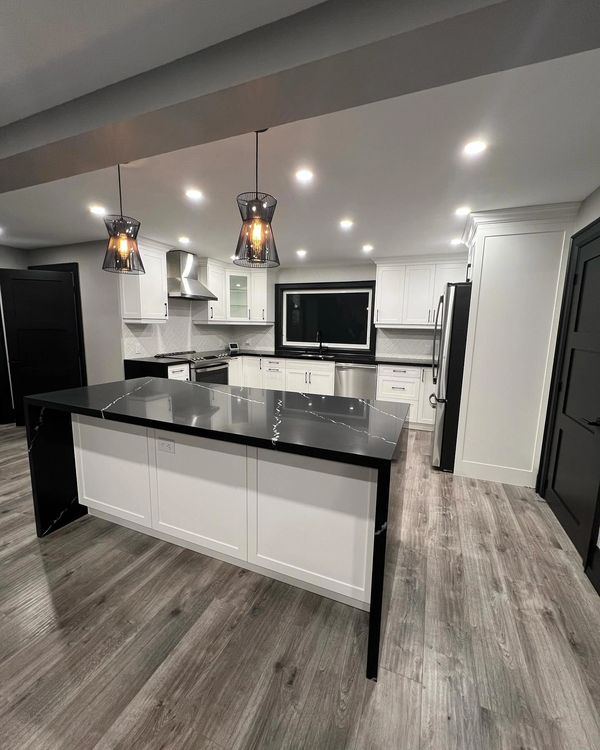 Modern kitchen with black and white color scheme and pendant lighting.