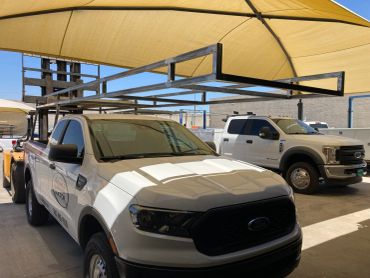 White trucks parked under yellow shade canopies.