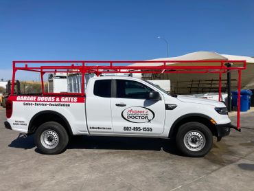 White garage door service truck with red ladder rack.
