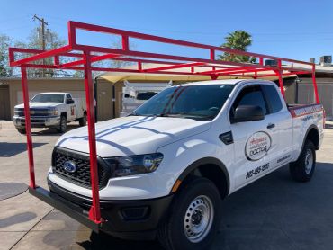 White pickup truck with red metal rack structure.
