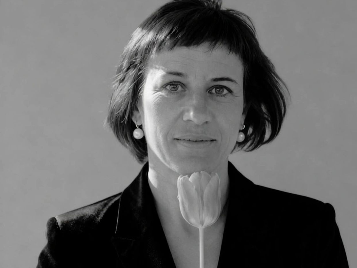 Black and white portrait of a woman holding a tulip close to her face.