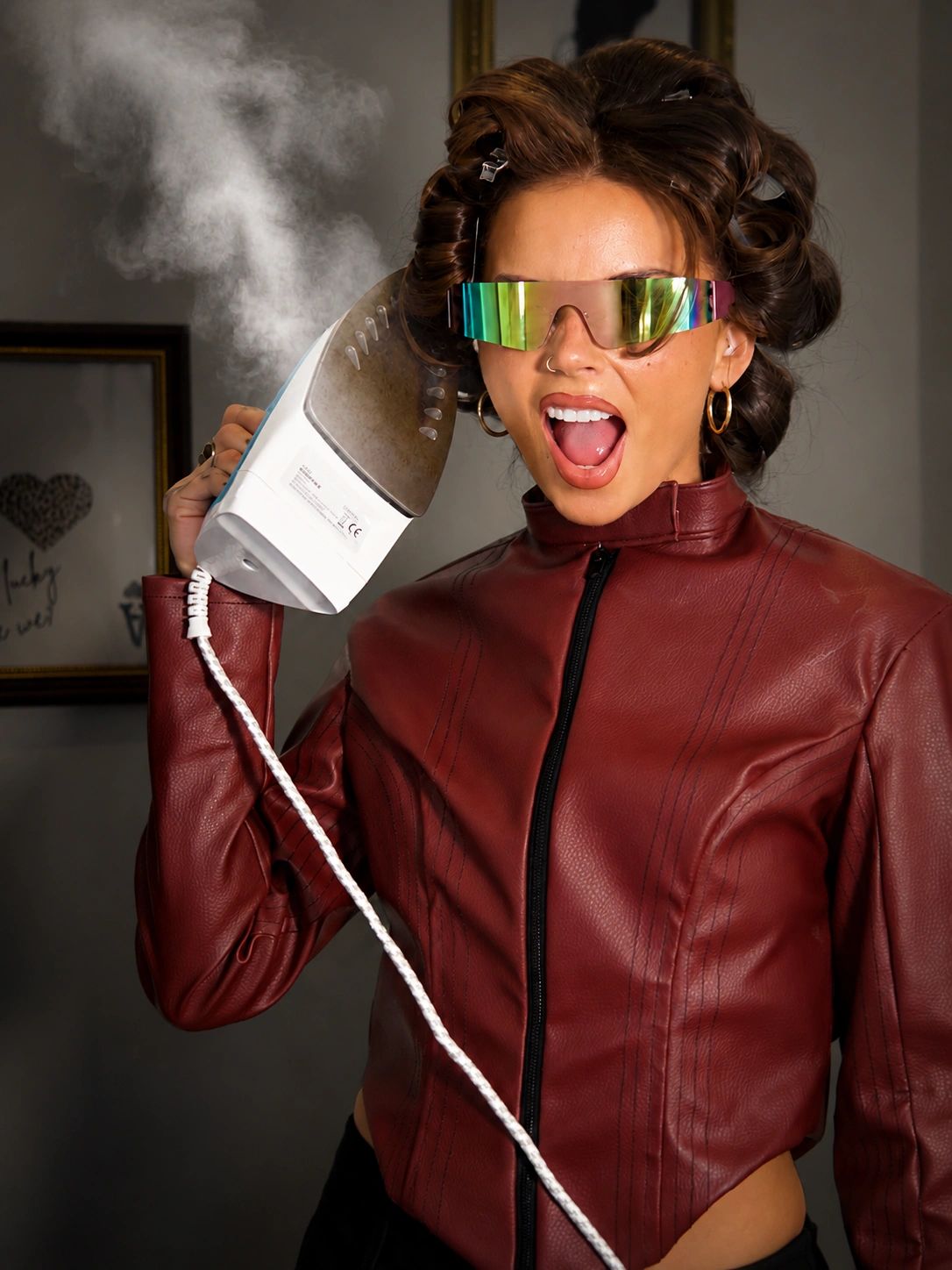 Woman using a steaming iron near her head.
