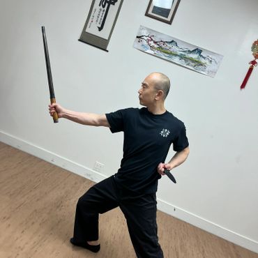 Man practicing martial arts with wooden swords in a studio.