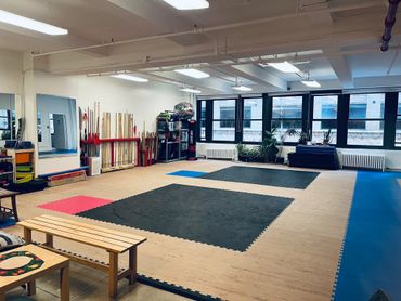 Spacious martial arts training room with mats and equipment.