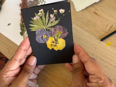 Hands holding a card with pressed flowers.
