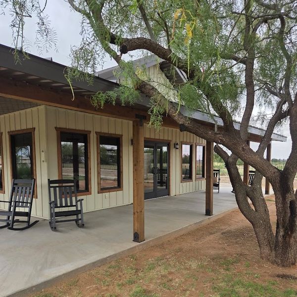 Front porch with rocking chairs and tree.