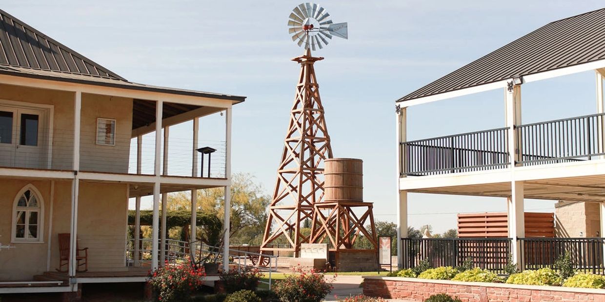 A wooden windmill between two buildings.