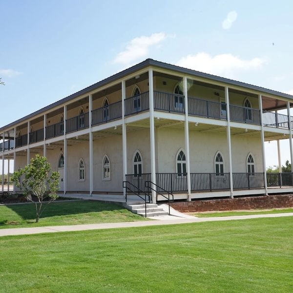 Two-story building with wraparound balcony and pointed arch windows.
