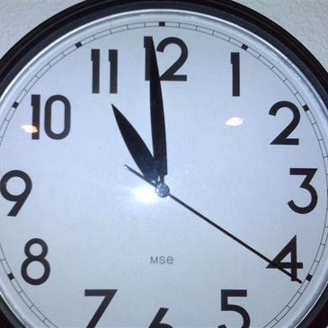A wall clock showing the time as 11:55 with a reflected light spot.