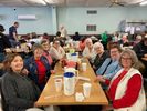 A group of people gathered around tables in a community hall.