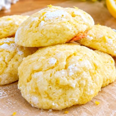 Soft lemon crinkle cookies dusted with powdered sugar on parchment paper.