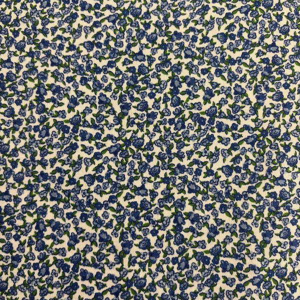 Close-up of fabric with blue and green floral pattern on a white background.