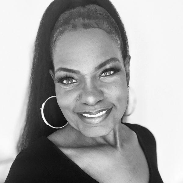 Black and white portrait of a smiling woman with large hoop earrings.