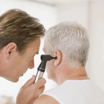 Doctor examining patient's ear with otoscope.