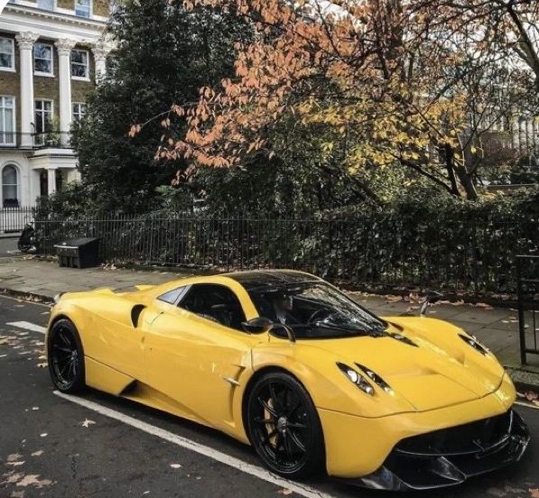Sleek yellow sports car parked on a leaf-strewn city street.