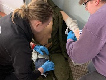 2 first aiders helping a casualty by applying bandages
