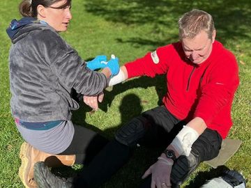 A female first aider bandaging a casaulty's arm