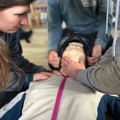 People removing a helmet from a training mankin.