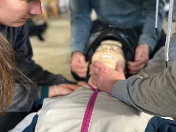 3 first aiders helping to remove a helmet from a casualty with a suspected spinal injury