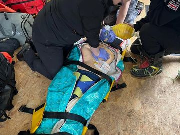 First Responders giving immediate life support to a casualty strapped into a scoop stretcher.