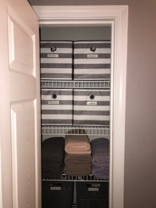 Organized linen closet using storage boxes.