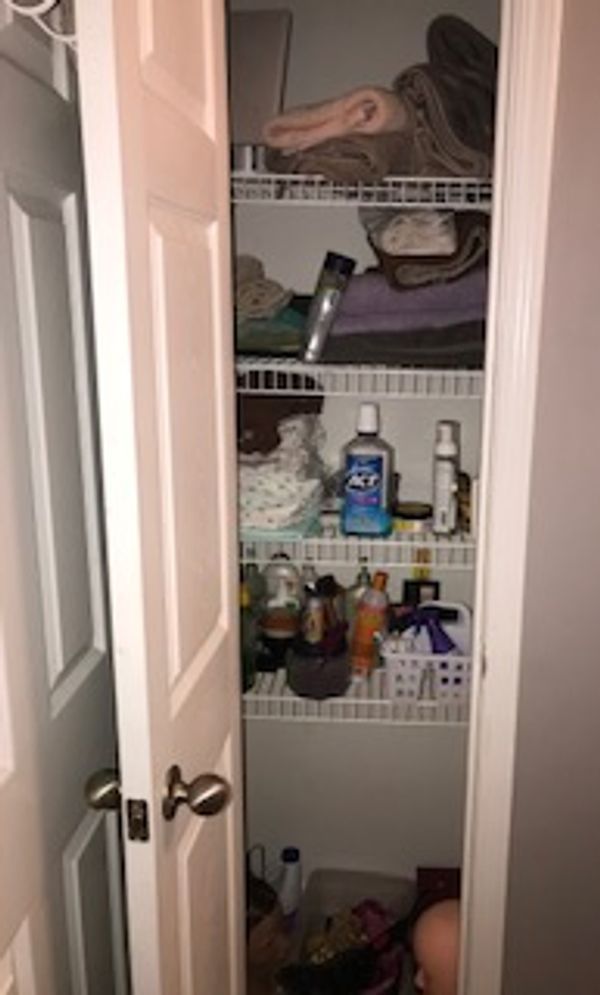 Unorganized towels and toiletries in a linen closet.