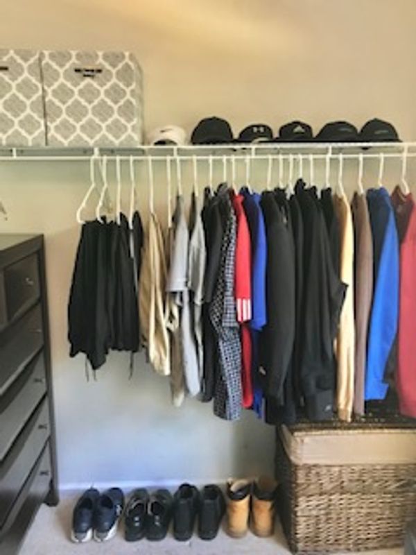 Neatly aligned clothes, shoes and hats in master closet.