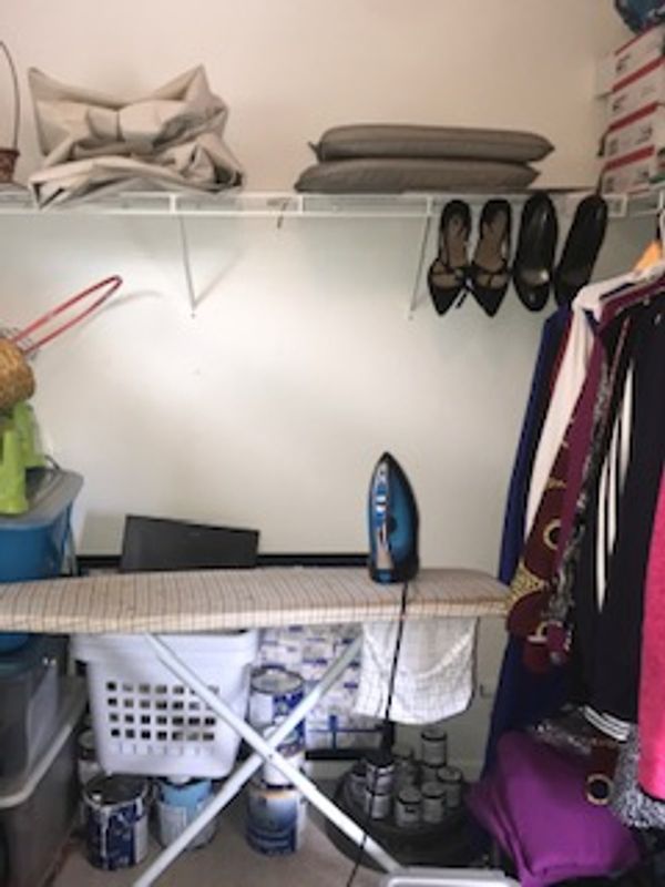 Ironing board in unorganized master closet.