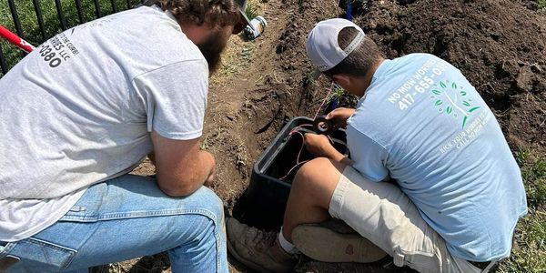 Two landscape employees laying down water lines.