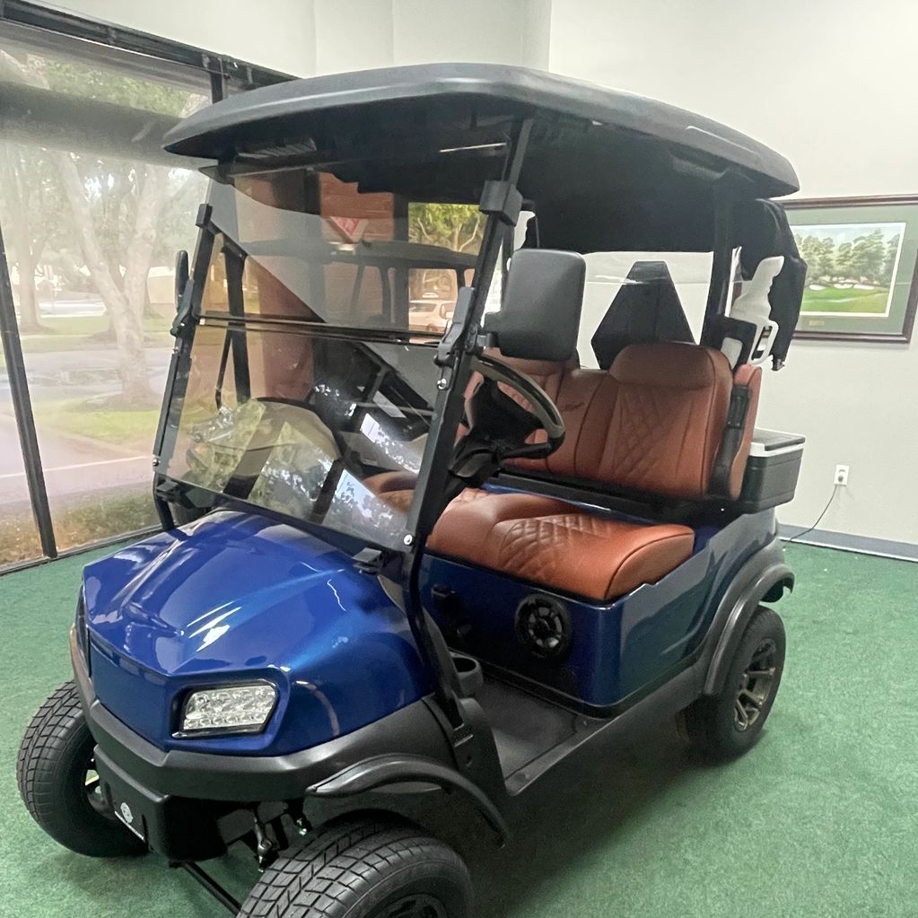 Stylish blue golf cart with brown leather seats indoors.