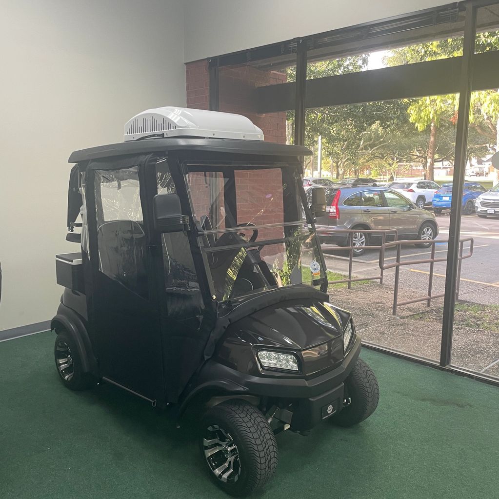 Black enclosed golf cart with air conditioning unit on roof.