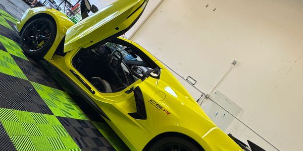 Yellow sports car with open door inside a garage.
