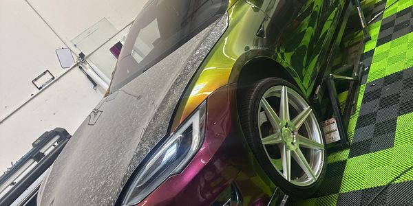 Colorful sports car on green and black checkered floor.