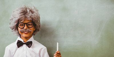 boy holder chalk in front of chalkboard