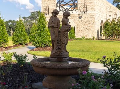 Stone statue of a man and woman in a garden fountain.