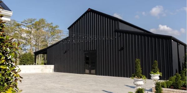 Modern black metal barn with outdoor string lights and greenery.
