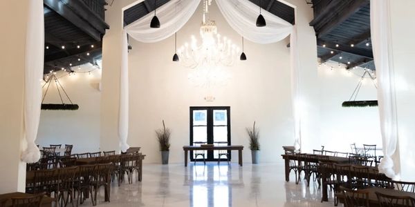 Elegant wedding ceremony setup with draped white fabric and chandelier.