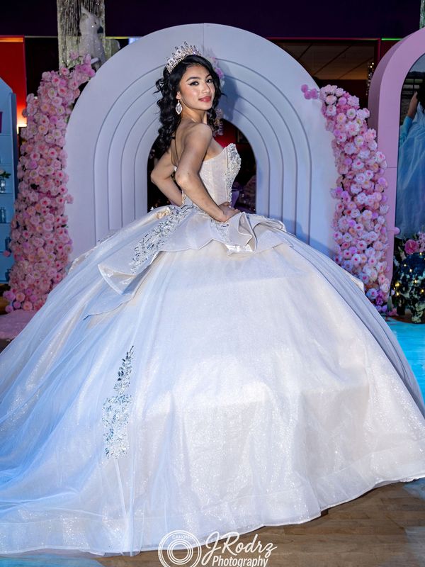 Young woman posing in an elegant white ball gown with a tiara.