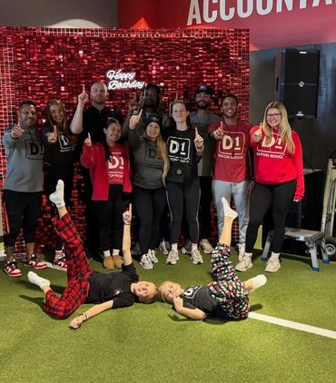 Group photo celebrating a birthday with everyone showing number one gesture.