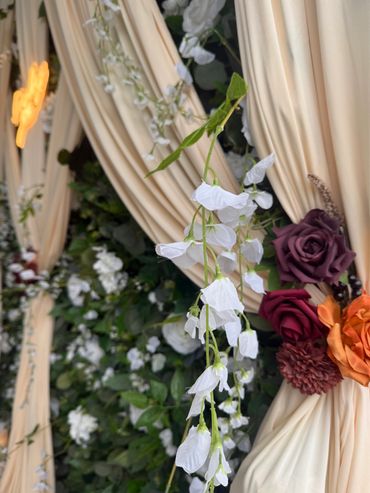 Delicate white flowers hang amidst cream drapes and vibrant roses.