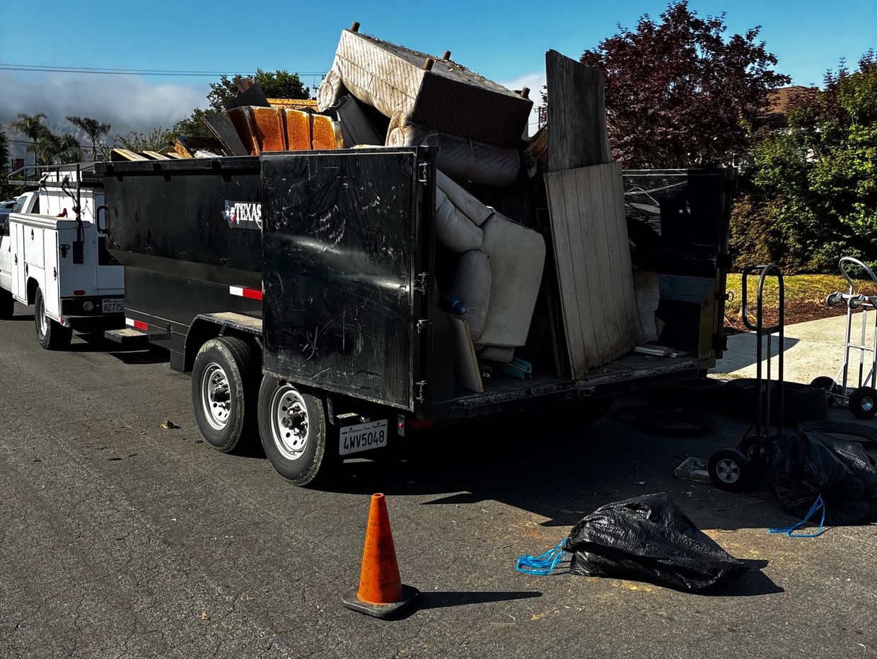 A trailer loaded with old furniture and debris parked on the street.