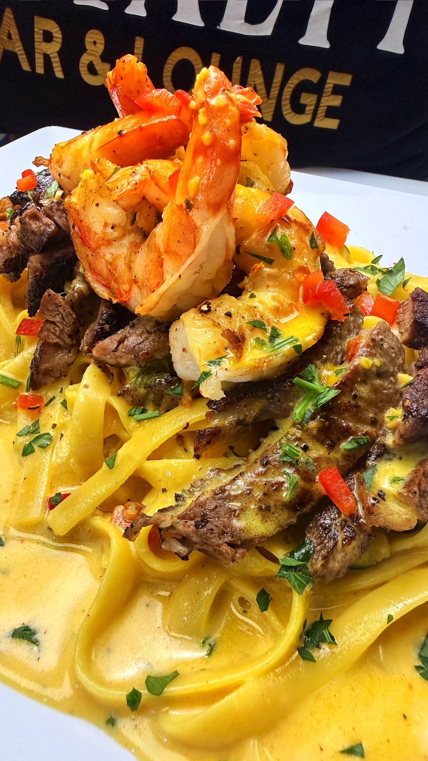 Creamy pasta topped with shrimp, steak, and fresh herbs.