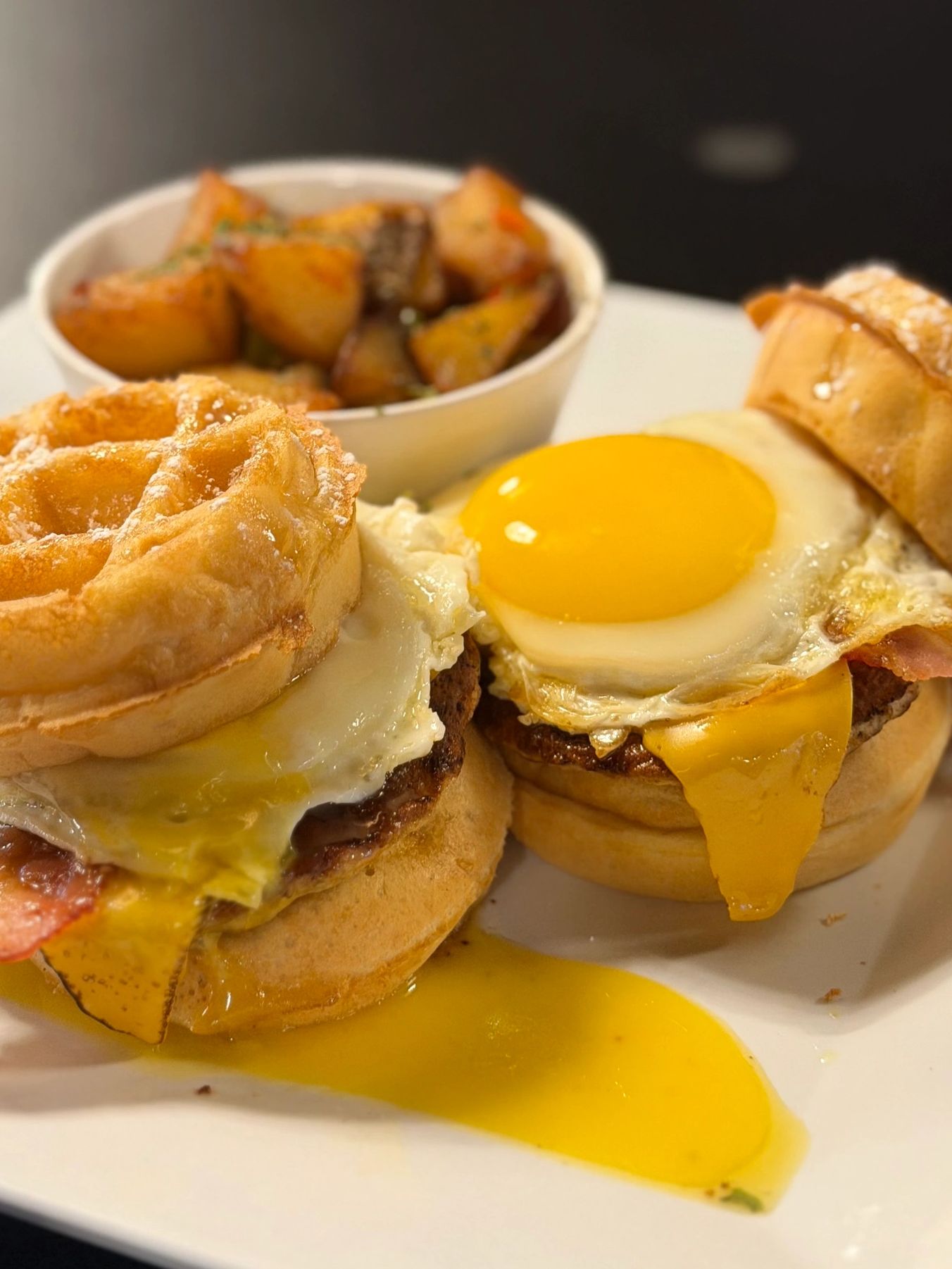 Breakfast sandwiches with fried eggs and a side of roasted potatoes.