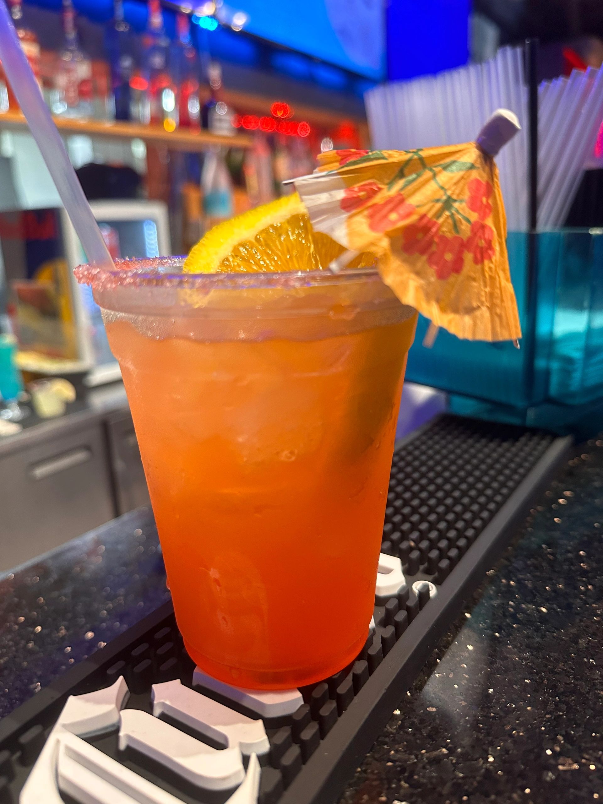 Orange tropical cocktail with a slice of orange and a paper umbrella.